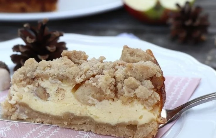 Apfel-Käsekuchen mit Streuseln auf einem Teller serviert.