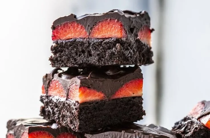 Erdbeer-Brownies mit Schoko-Ganache auf einem Teller angerichtet.