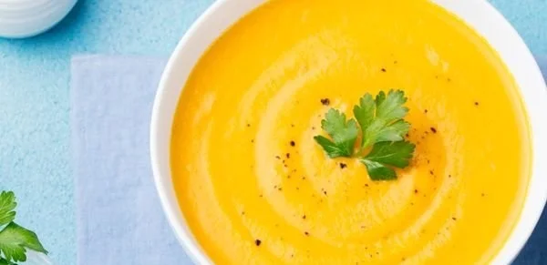 Kürbis-Mango-Suppe in der Schüssel garniert mit Kräutern
