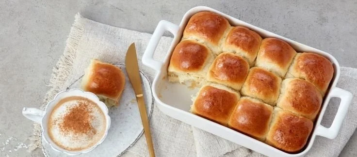 Frisch gebackene Milchbrötchen auf einem Holzbrett, ideal für das Frühstück.