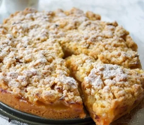 Omas Apfelkuchen mit Streusel auf einem Teller, frisch gebacken und verführerisch.