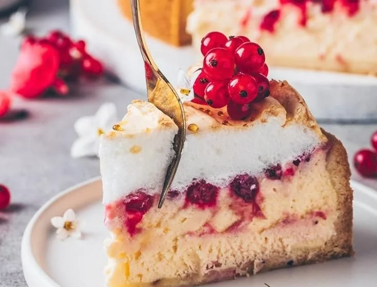 Veganer Baiser-Käsekuchen auf einem Teller mit frischen Früchten